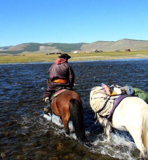 A horse guide Lkhagva is crossing the river.